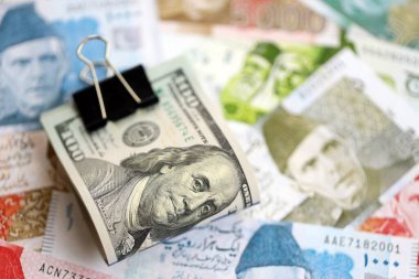 Amerikan dolarlarının rulosu Pakistan 'daki büyük miktardaki banknotların üzerinde yatıyor. Amerikan para demeti Pakistan 'ın para banknotlarında yatıyor. Pakistan 'da ekonomi ve döviz kuru kavramı