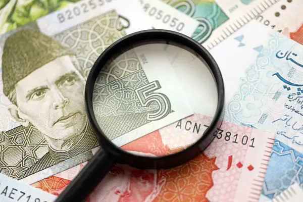 Pakistan banknotları ve büyüteç. Pakistan 'ın mevcut para ve büyüteç faturaları büyük miktarda masanın üzerinde duruyor. Pakistan 'da mali izleme ve vergilendirme kavramı