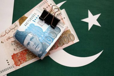 Pakistan bayrağı üzerinde Pakistan banknotları. Pakistan 'ın mevcut para faturaları büyük miktarlarda pankartta yatıyor. Pakistan 'da ekonomi ve ticaret kavramı