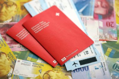 İsviçre frangı banknotları ve biletli pasaport. Mevcut banknotlar ve biyometrik geçiş kartları büyük miktarda masada yatıyor. İsviçre 'de seyahat ve tatil kavramı