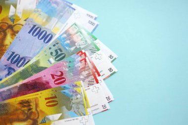 Mavi arka planda İsviçre frangı banknotları. Mevcut frank para faturaları büyük miktarda masada yatıyor. İsviçre 'de iş ve yatırım kavramı