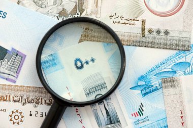 Birleşik Arap Emirlikleri kara para birimi banknotları ve büyüteç yakın çekim. Finansal izleme ve vergilendirme kavramı