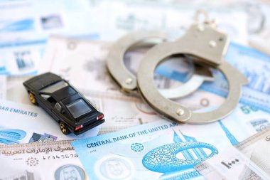 Birleşik Arap Emirlikleri kara para birimi faturaları ve kelepçeli oyuncak araba. Araba kazası kavramı.