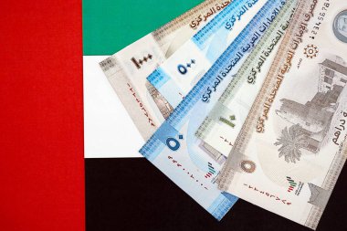 Birleşik Arap Emirlikleri kara para birimi banknotları bayrağa yakın duruyor. İş ve yatırım kavramı