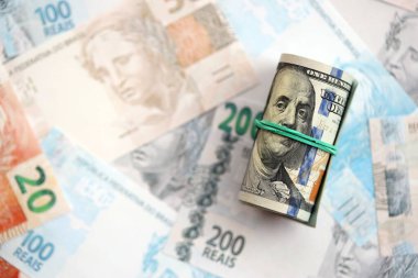 Bir tomar Amerikan doları büyük miktarda Brezilya banknotlarının üzerinde yatıyor. Amerikan parası Brezilya 'nın para akışında yatıyor. Brezilya 'da ekonomi ve döviz kuru kavramı