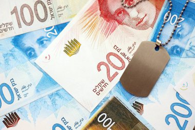 İsrail Yeni Şekelleri 'nin banknotları ve askeri simgesi. İsrail 'in mevcut para faturaları ve künyeleri büyük miktarda masada yatıyor. İsrail 'de askerlik kavramı