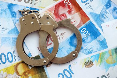 Israel New Shekels banknotları ve kelepçeleri. İsrail 'in şu anki para ve kelepçeleri büyük miktarda masada yatıyor. İsrail 'de suçlu kavramı