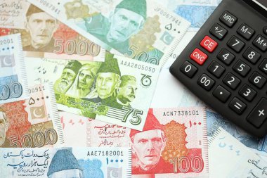 Pakistan banknotları ve hesap makinesi. Pakistan 'ın mevcut para ve hesap makinesi büyük miktarda masada yatıyor. Pakistan 'da vergi ve para sayımı kavramı