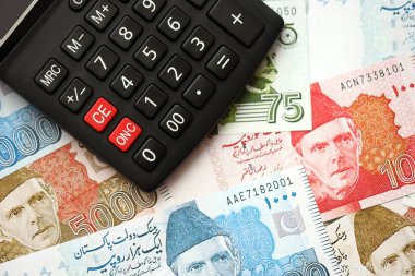 Pakistan banknotları ve hesap makinesi. Pakistan 'ın mevcut para ve hesap makinesi büyük miktarda masada yatıyor. Pakistan 'da vergi ve para sayımı kavramı