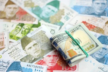 Amerikan dolarları yığını Pakistan Rupi banknotlarının büyük bir miktarına yakın duruyor. Amerikan para demeti Pakistan 'ın para banknotlarında yatıyor. Pakistan 'da ekonomi ve döviz kuru kavramı
