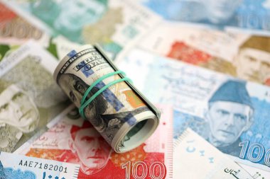 Amerikan dolarlarının rulosu Pakistan 'daki büyük miktardaki banknotların üzerinde yatıyor. Amerikan para demeti Pakistan 'ın para banknotlarında yatıyor. Pakistan 'da ekonomi ve döviz kuru kavramı