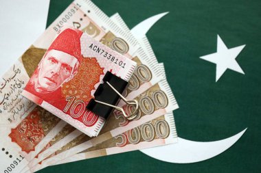 Pakistan bayrağı üzerinde Pakistan banknotları. Pakistan 'ın mevcut para faturaları büyük miktarlarda pankartta yatıyor. Pakistan 'da ekonomi ve ticaret kavramı