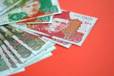 Pakistan kırmızı arka planda banknotlar halinde. Pakistan 'ın mevcut para faturaları büyük miktarda masada yatıyor. Pakistan 'da iş ve yatırım kavramı
