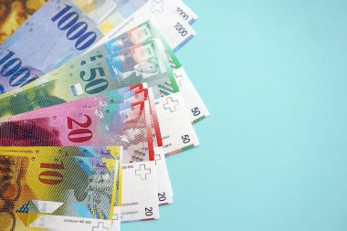 Mavi arka planda İsviçre frangı banknotları. Mevcut frank para faturaları büyük miktarda masada yatıyor. İsviçre 'de iş ve yatırım kavramı