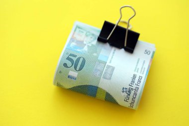 Sarı arka planda İsviçre frangı banknotları. Mevcut frank para faturaları büyük miktarda masada yatıyor. İsviçre 'de iş ve yatırım kavramı