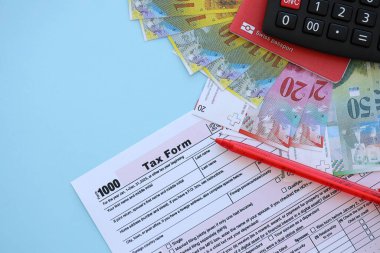 İsviçre frangı banknotları ve mavi üzerine vergi formu. Mevcut para faturaları vergi formu ve bayraklarda yatıyor. İsviçre 'de vergilendirme kavramı