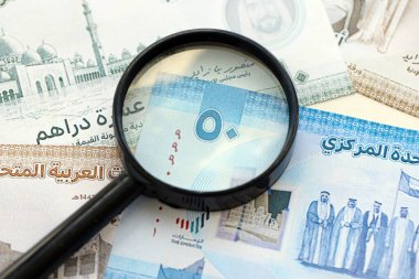 Birleşik Arap Emirlikleri kara para birimi banknotları ve büyüteç yakın çekim. Finansal izleme ve vergilendirme kavramı