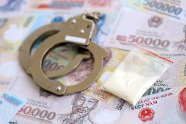 Vietnam dong para birimi faturaları ve kelepçeli kokain paketi. Uyuşturucu suçları kavramı