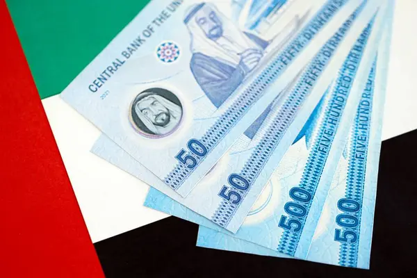 Birleşik Arap Emirlikleri kara para birimi banknotları bayrağa yakın duruyor. İş ve yatırım kavramı