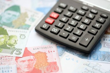 Pakistan banknotları ve hesap makinesi. Pakistan 'ın mevcut para ve hesap makinesi büyük miktarda masada yatıyor. Pakistan 'da vergi ve para sayımı kavramı