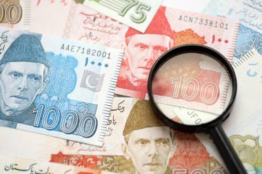Pakistan banknotları ve büyüteç. Pakistan 'ın mevcut para ve büyüteç faturaları büyük miktarda masanın üzerinde duruyor. Pakistan 'da mali izleme ve vergilendirme kavramı