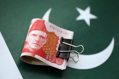 Pakistan bayrağı üzerinde Pakistan banknotları. Pakistan 'ın mevcut para faturaları büyük miktarlarda pankartta yatıyor. Pakistan 'da ekonomi ve ticaret kavramı