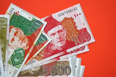 Pakistan kırmızı arka planda banknotlar halinde. Pakistan 'ın mevcut para faturaları büyük miktarda masada yatıyor. Pakistan 'da iş ve yatırım kavramı