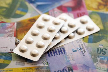 İsviçre frangı ve ilaç hapları. Mevcut para ve uyuşturucu banknotları büyük miktarda masada yatıyor. İsviçre 'de ilaç ve eczane kavramı