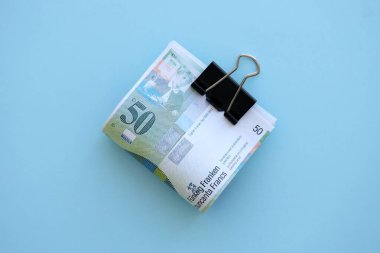 Mavi arka planda İsviçre frangı banknotları. Mevcut frank para faturaları büyük miktarda masada yatıyor. İsviçre 'de iş ve yatırım kavramı