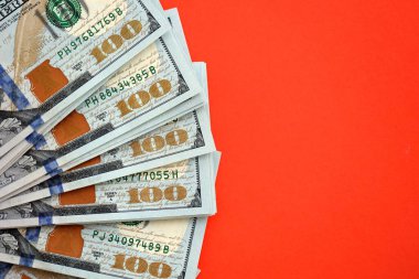 Kırmızı arka planda büyük miktarda yüz dolarlık banknot var. ABD 'de vergilendirme ve para yapma kavramı
