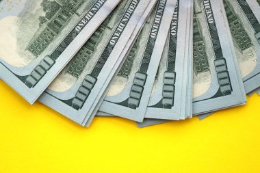 Sarı arka planda büyük miktarda Birleşik Devletler 100 dolarlık banknotları. ABD 'de vergilendirme ve para yapma kavramı