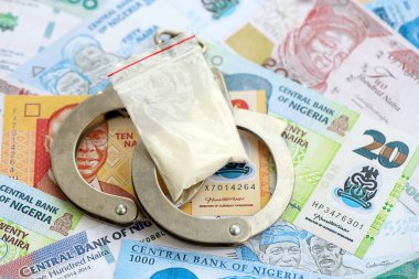 Nijerya naira para birimi faturaları ve kelepçeli kokain paketi. Uyuşturucu suçları kavramı