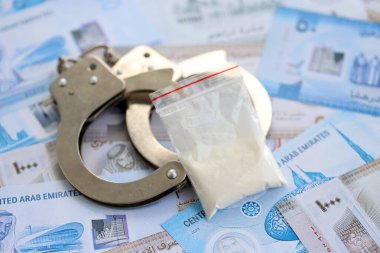 Birleşik Arap Emirlikleri kara para birimi faturaları ve kelepçeli kokain paketleri. Uyuşturucu suçları kavramı
