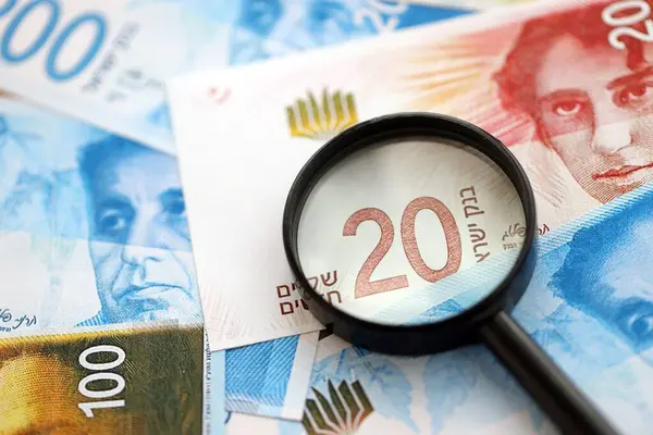 Israel New Shekels banknotları ve büyüteç. Şu anki İsrail 'in yüksek meblağlı faturaları masanın üzerinde yatıyor. İsrail 'de mali izleme ve vergilendirme kavramı