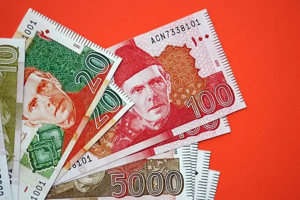 Pakistan kırmızı arka planda banknotlar halinde. Pakistan 'ın mevcut para faturaları büyük miktarda masada yatıyor. Pakistan 'da iş ve yatırım kavramı