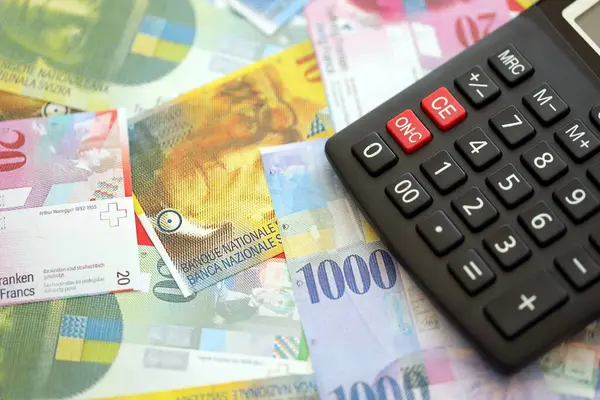 İsviçre frangı banknotları ve hesap makinesi. Mevcut frank para faturaları ve calc büyük miktarda masada yatıyor. İsviçre 'de vergilendirme ve para konsepti