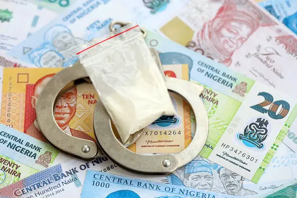 Nijerya naira para birimi faturaları ve kelepçeli kokain paketi. Uyuşturucu suçları kavramı
