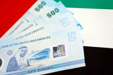 Birleşik Arap Emirlikleri kara para birimi banknotları bayrağa yakın duruyor. İş ve yatırım kavramı