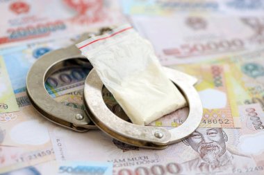 Vietnam dong para birimi faturaları ve kelepçeli kokain paketi. Uyuşturucu suçları kavramı