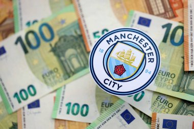 KYIV, UKRAINE - 23 Şubat 2025 Manchester City FC futbol kulübü rozeti büyük miktarda EURO para banknotlarının üzerinde yatıyor