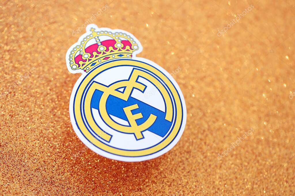KYIV, UKRAINE - FEBRUARY 23, 2025 Real Madrid CF football club badge lies on golden yellow glitter background banner