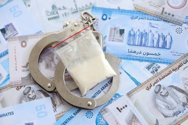 Birleşik Arap Emirlikleri kara para birimi faturaları ve kelepçeli kokain paketleri. Uyuşturucu suçları kavramı