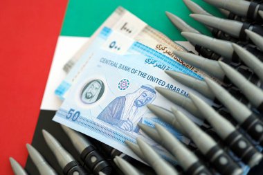 Birleşik Arap Emirlikleri kara para birimi banknotları ve bayraklar üzerinde tüfek mermileri. Savaş ve silah satışı kavramı