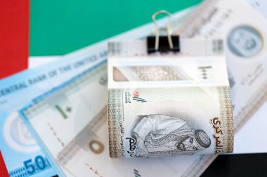 Birleşik Arap Emirlikleri kara para birimi banknotları bayrağa yakın duruyor. İş ve yatırım kavramı