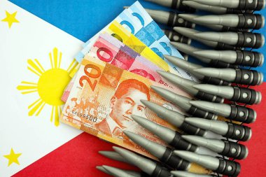 Filipinler para birimi banknotları ve bayraklar üzerinde tüfek mermileri. Savaş ve silah satışı kavramı