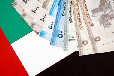 Birleşik Arap Emirlikleri kara para birimi banknotları bayrağa yakın duruyor. İş ve yatırım kavramı