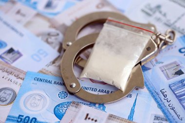 Birleşik Arap Emirlikleri kara para birimi faturaları ve kelepçeli kokain paketleri. Uyuşturucu suçları kavramı