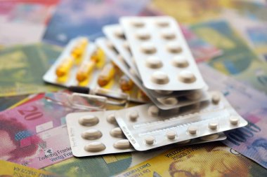 İsviçre frangı ve ilaç hapları. Mevcut para ve uyuşturucu banknotları büyük miktarda masada yatıyor. İsviçre 'de ilaç ve eczane kavramı