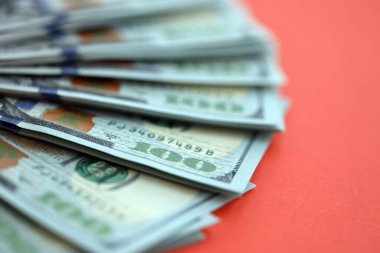 Kırmızı arka planda büyük miktarda yüz dolarlık banknot var. ABD 'de vergilendirme ve para yapma kavramı