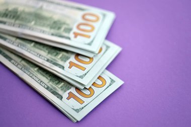 Mor arka planda büyük miktarda yüz dolarlık banknotlar. ABD 'de vergilendirme ve para yapma kavramı